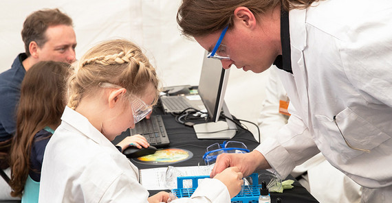 Ein Wissenschaftler betreut ein Mädchen bei einem chemischen Experiment