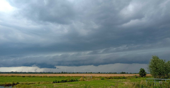 Blick auf eine Wiese, im Hintergrund dunkle Gewitterwolken