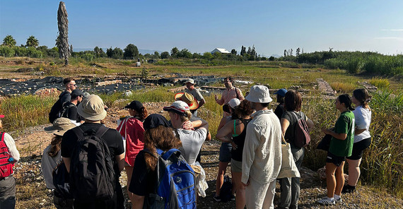 Studierende an Ausgrabungsstätte in praller Sonne.
