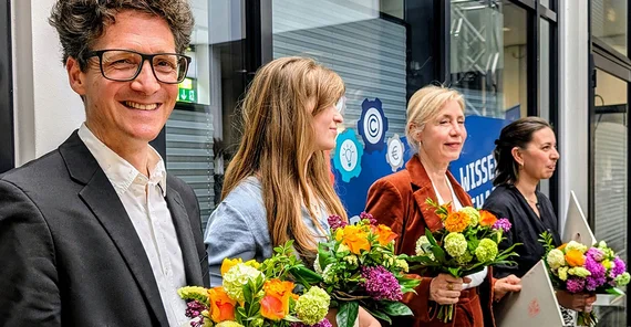 Mneschen bei einer Preisverleihung mit Blumen in den Händen.