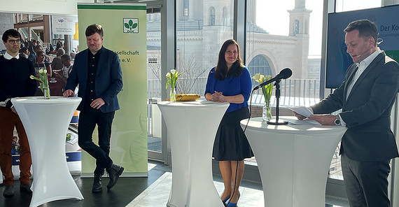 Das Foto von der Eröffnung eines Kongresses in Potsdam zeigt eine Frau und drei Männer an Stehtischen, von denen einer gerade eine Rede hält. Foto: Antje Horn-Conrad