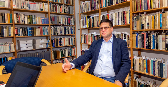 Gideon Botsch im Gespräch. Hinter ihm eine Raumecke einer vollen Bücherwand.