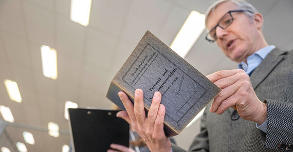 Ralf Müller hält das Personalverzeichnis der Pädagogischen Hochschule aus dem Studienjahr 1949/50 in den Händen.