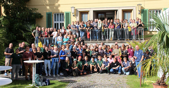 Teilnehmende der Jahrestagung des Verbands Botanischer Gärten 2025 im Botanischen Garten Potsdam posieren für ein Gruppenbild. Es sind sehr viele Personen auf dem Bild zu erkennen.