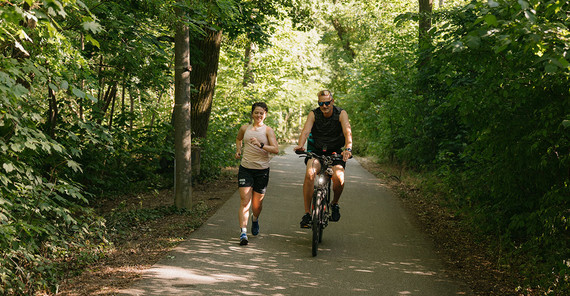 Lena Sonntag mit ihrem Trainer am Templiner See. Sie geht, er fährt daneben Rad.