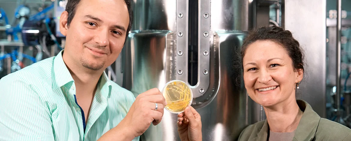 Dr Lena Hochrein and Professor Ruben R. Rosencrantz are holding up a Petri dish covered in growth. - 