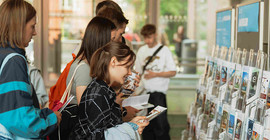Einige junge Menschen stehen vor einem Display mit Flyern