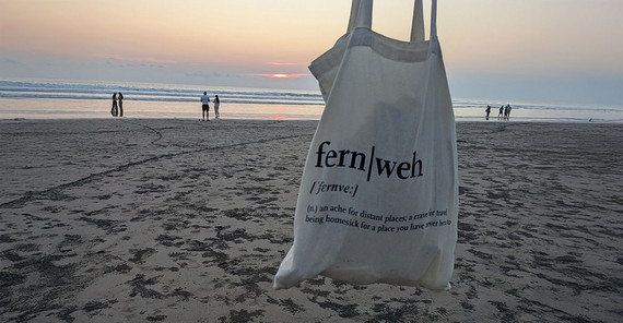 Strand in Seminyak im Hintergrund. In den Vordergrund wird ein Jutebeutel mit dem Aufdruck "fernweh" gehalten.