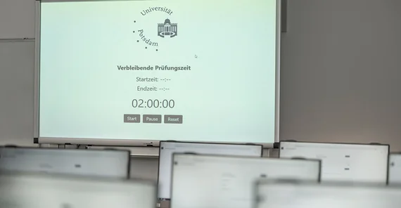 Blick über mehrere Bildschirme auf ein Whiteboard.