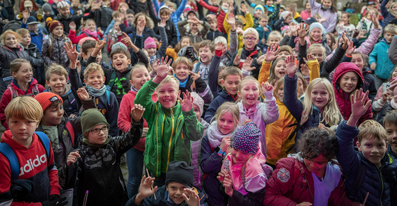 Eine große Gruppe Kinder jubelt vor einer Bühne