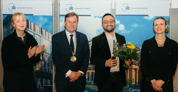 Vier Menschen stehen bei einer Preisverleihung zusammen