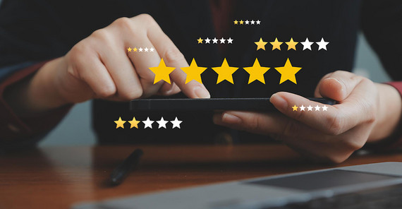 Hände eines Menschen, der ein Tablet hält, drumherum sind Sterne von Bewertungen eingeblendet