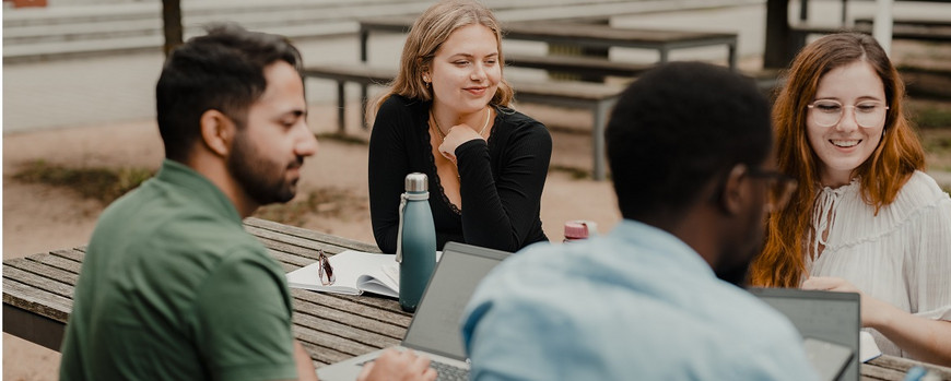 Profs sitting outside on campus with students