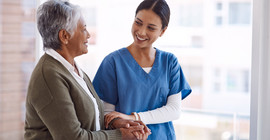 Eine Pflegerin stützt eine ältere Frau.