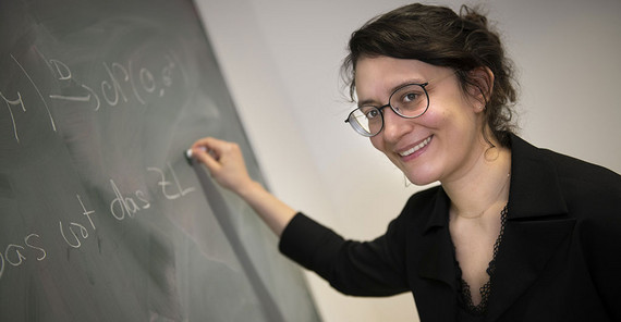 Frau steht an der Tafel und schreibt etwas