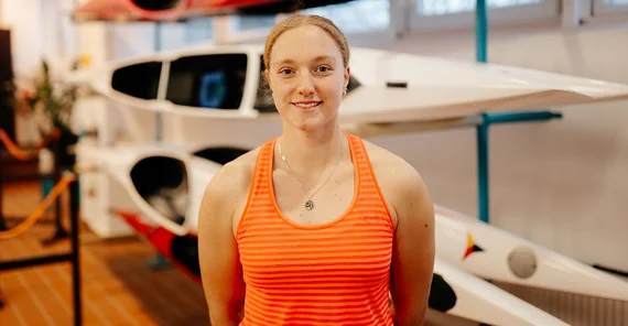 Hannah Spielhagen im Portrait in Sportkleidung vor Kanus.